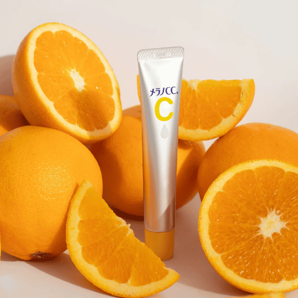 Frisk appelsin med en ansigtspleje-krem med C-vitamin foran, hvilket fremhæver naturlige ingredienser til hudpleje.