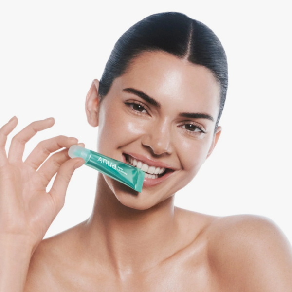 Smilende kvinde med sund hud holder en ansigtscreme fra MySkin, fokus på hudpleje og skønhed.