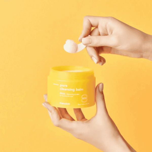 Følende hånd med hudplejeprodukt, pore cleansing balm i gul farve, til dybderensende hudpleje, til urenheder og pimples. Harmlös og effektiv lugtfri formel.