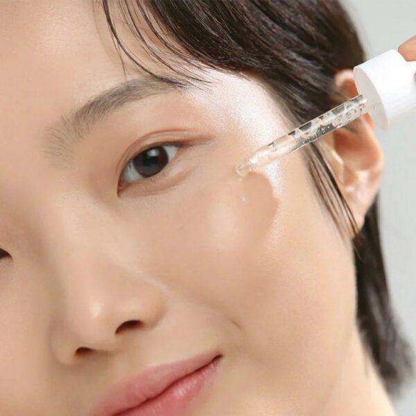 Nærbillede af en kvindes ansigt, der bruger en hudpleje dråbe pipette til behandling af huden, fokuseret på ren hudpleje og ansigtspleje.